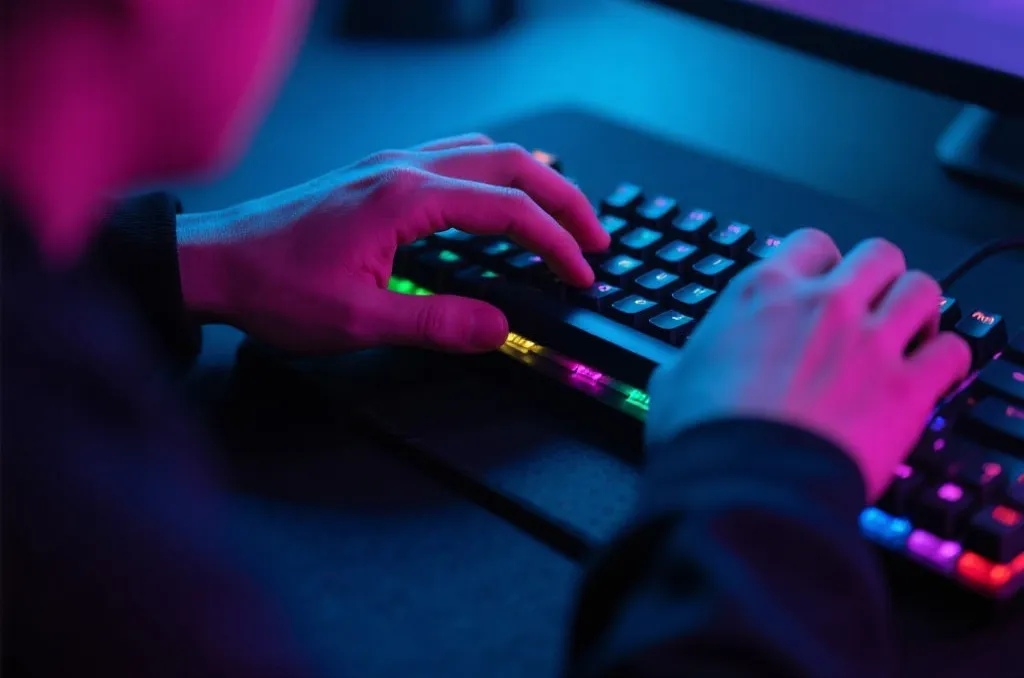 Close-up of a pro gamer hands on an RGB mechanical keyboard with glowing ambient light